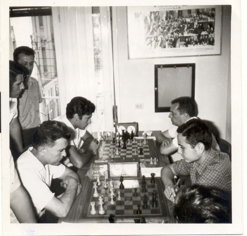 Από το αρχείο του Μενέλαου Ταφτσόγλου. Άλλη μια φωτογραφία ιστορική του 1970 στην οποία φαίνεται ο Μ.Ταφτσόγλου να αγωνίζεται αριστερά στη 2η σκακιέρα, ενώ όρθιος (δίπλα στο παράθυρο) παρακολουθεί ο Ευκλείδης Φωτιάδης.